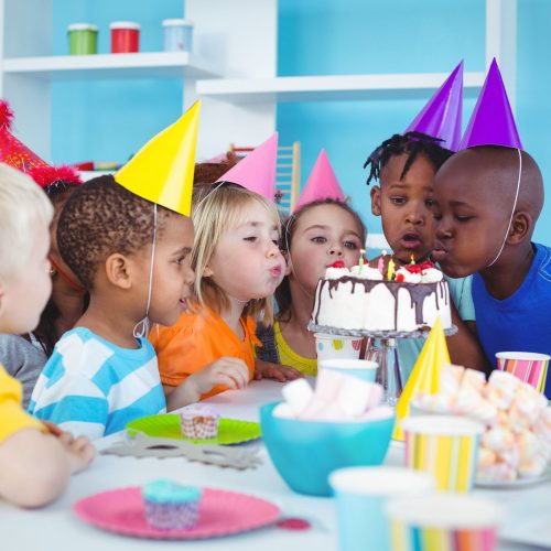 Excited kid enjoying a birthday party near the cake